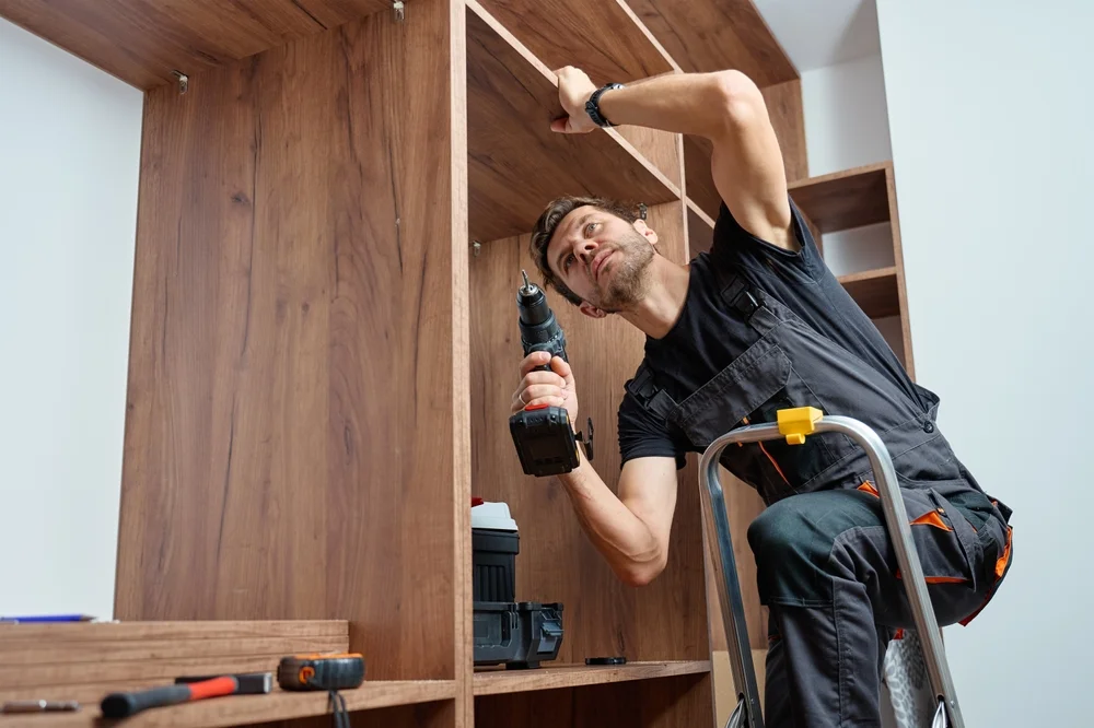 man working on wood cabnet in home